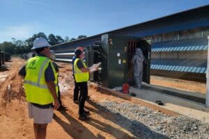 A group of men in yellow vests and hard hats near a large metal door, participating in arc flash training.
